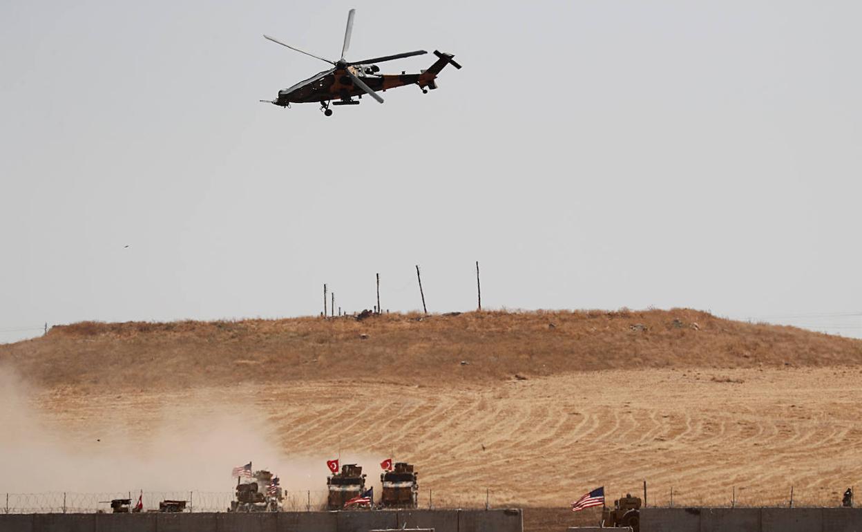 Un helicóptero militar sobrevuela sobre los blindados turcos y estadounidenses, en el norte de Siria.