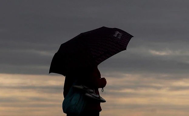 Una persona con un paraguas en la playa de la Malvarrosa, el domigo.