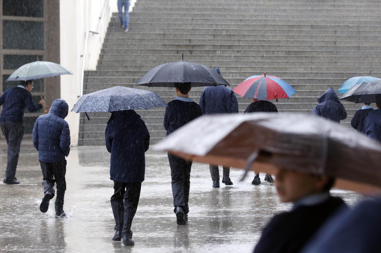 Varios viandantes se protegen de la lluvia ayer en Valencia. 