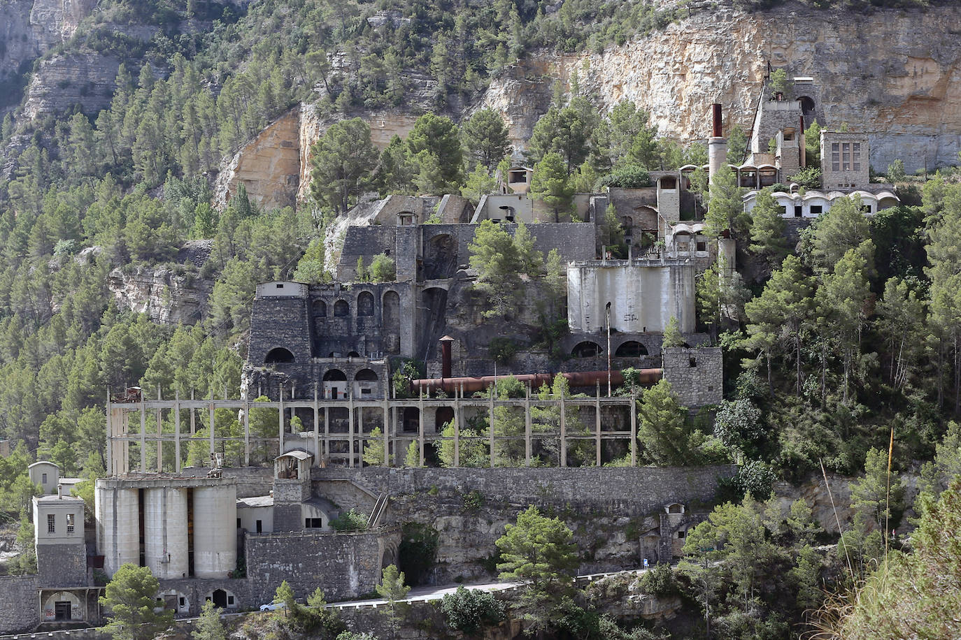 La cementera de Benagéber (Valencia) | La enorme construcción todavía se contempla desde lo lejos, como un colosal castillo de hormigón entre agua y maleza. Construida en la década de los cuarenta, fue gestionada por la misma empresa que se encargó del embalse, Portolés y Cía, que se convertiría en una de las principales compañías de obras públicas tras la Guerra Civil. La construcción del pantano de Contreras también corrió a cargo de esta firma, prueba de su estrecha colaboración laboral con el gobierno franquista. En aquella época, la mayoría de los habitantes de Benagéber eran los trabajadores de las obras del embalse y la cementera. Por ello, cuando en 1955 finalizaron los trabajos para la formación del pantano, la mayoría de la población emigró y el lugar quedó sumido en la escalofriante quietud que, a día de hoy, le sigue caracterizando. 