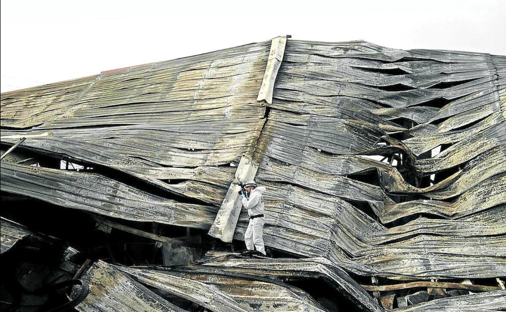 Un agente del ESIN inspecciona el tejado de una factoría quemada en busca de pruebas.