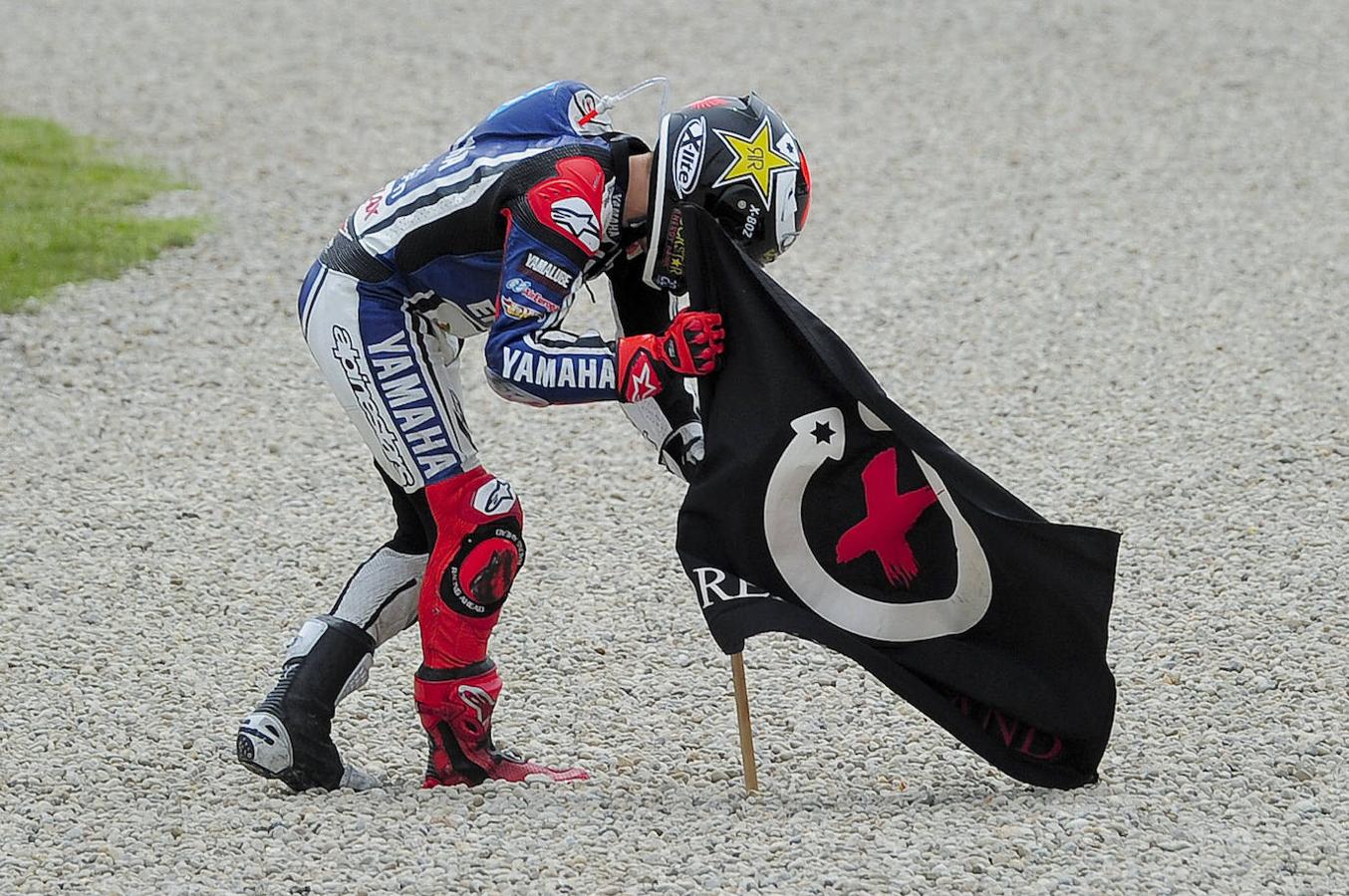 Jorge Lorenzo planta la bandera de su club de fans después de ganar la carrera de MotoGP del Gran Premio de Catalunya en 2012.