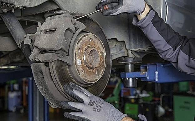 Un mecánico revisa los discos de frendo de un coche.
