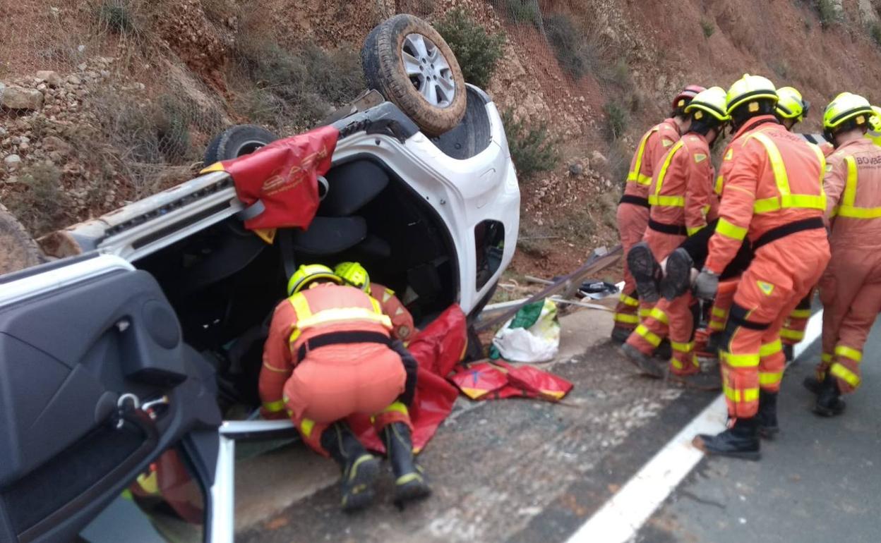 Una delas personas heridas en el accidente en la carretera N-III en el término de Buñol, con el coche volcado. 