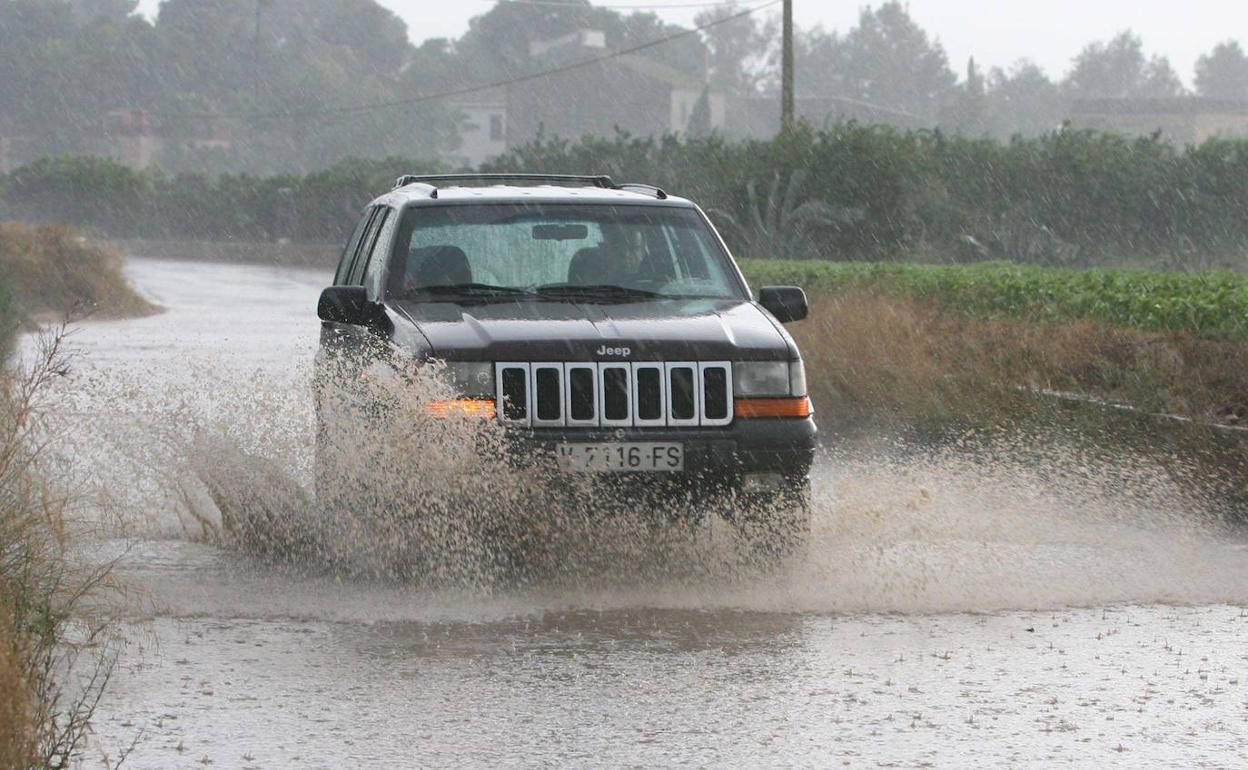 Un coche circula por una carretera inundada. 