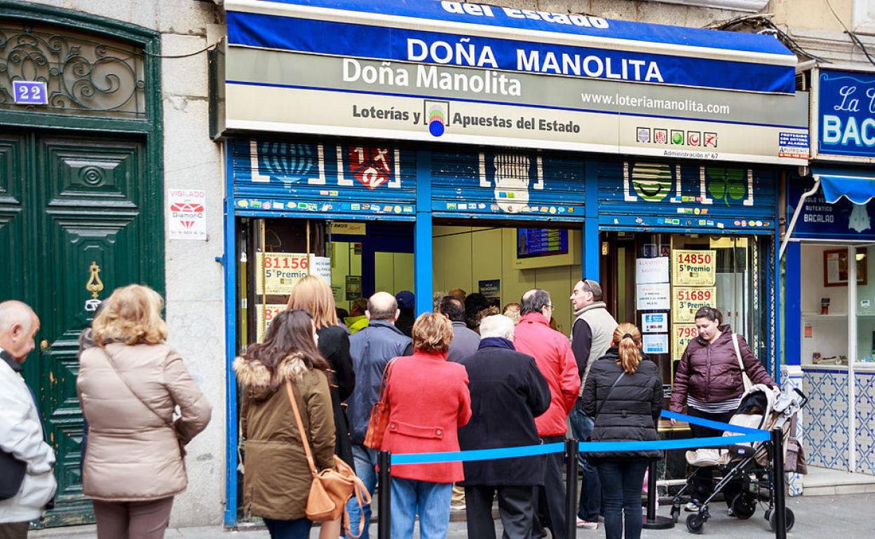 Varias personas hacen cola para comprar lotería en Doña Manolita, en Madrid.