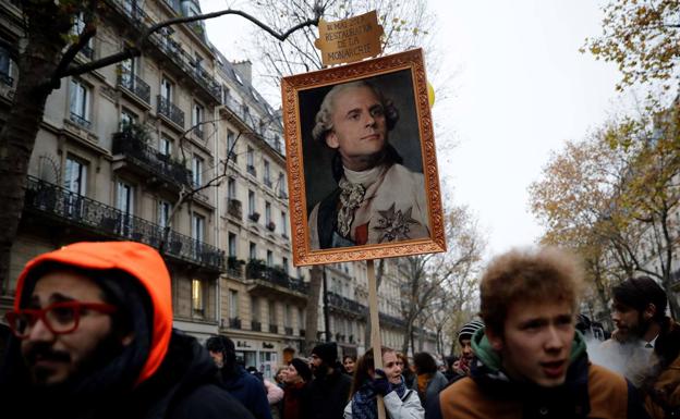 Una mujer transporta un cartel del 'rey Macron'.