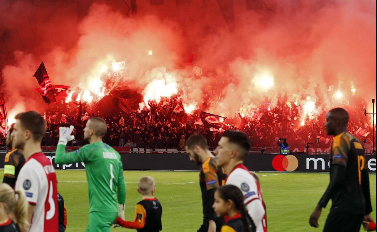 Aficionados del Ajax encienden bengalas en la salida de los equipos.