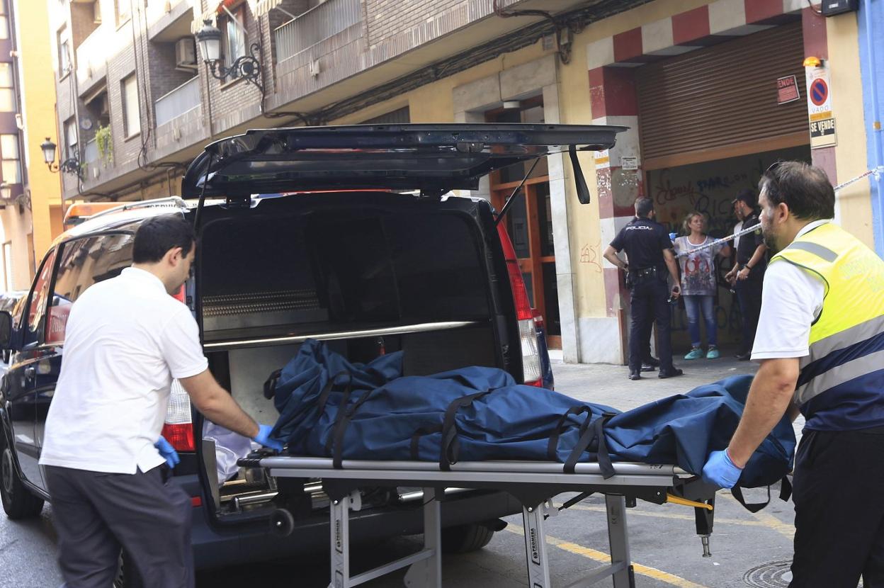 Dos empleados del retén fúnebre introducen el cadáver de la víctima en un vehículo. 