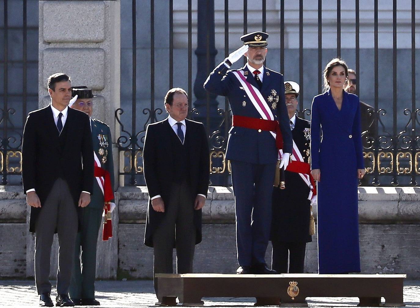 Felipe VI, acompañado por la Reina Letizia, ha presidido este lunes la ceremonia de la Pascua Militar en el Palacio Real. Para la ocasión, Doña Letizia ha elegido un elegante vestido de estilo esmoquin en azul intenso. La Reina ha combinado el diseño, largo hasta los pies, con unos zapatos stilettos en color negro y un peinado recogido acabado en un moño bajo.