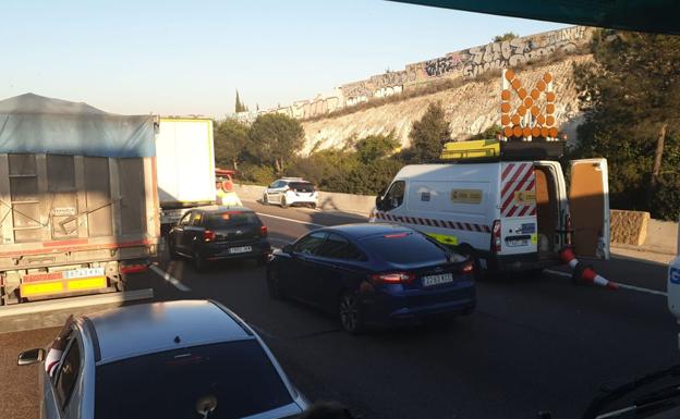 Un coche de Policía Local y el atasco, cerca del accidente.