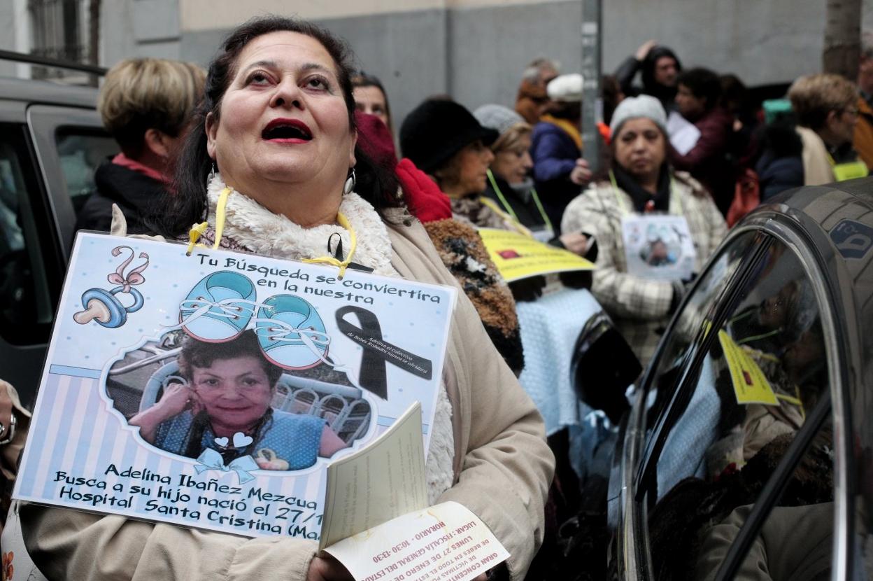 Una mujer sujeta un cartel en el que se ve la foto de una de las madres de bebés robados. 