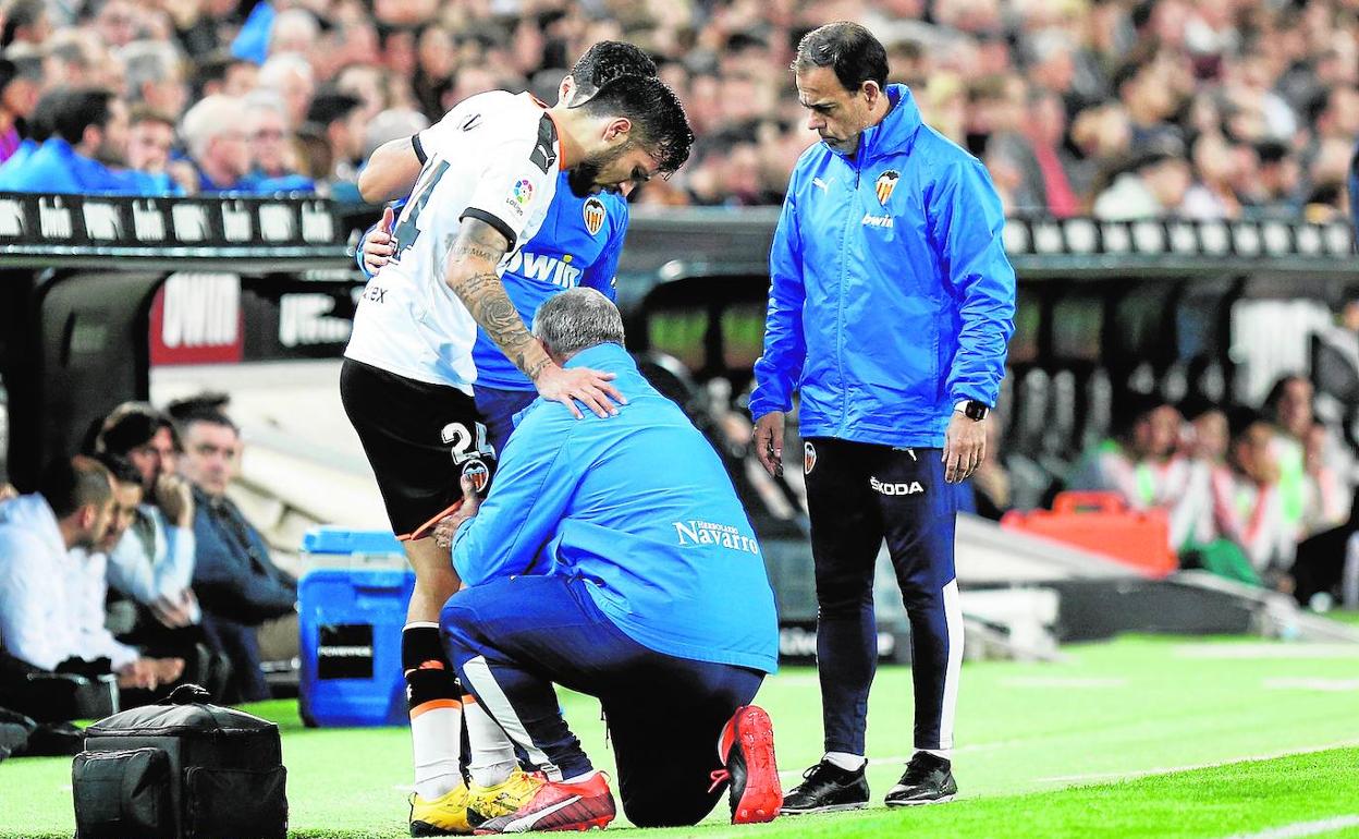 Los sanitarios del Valencia atienden a Garay antes de que se marchase lesionado.