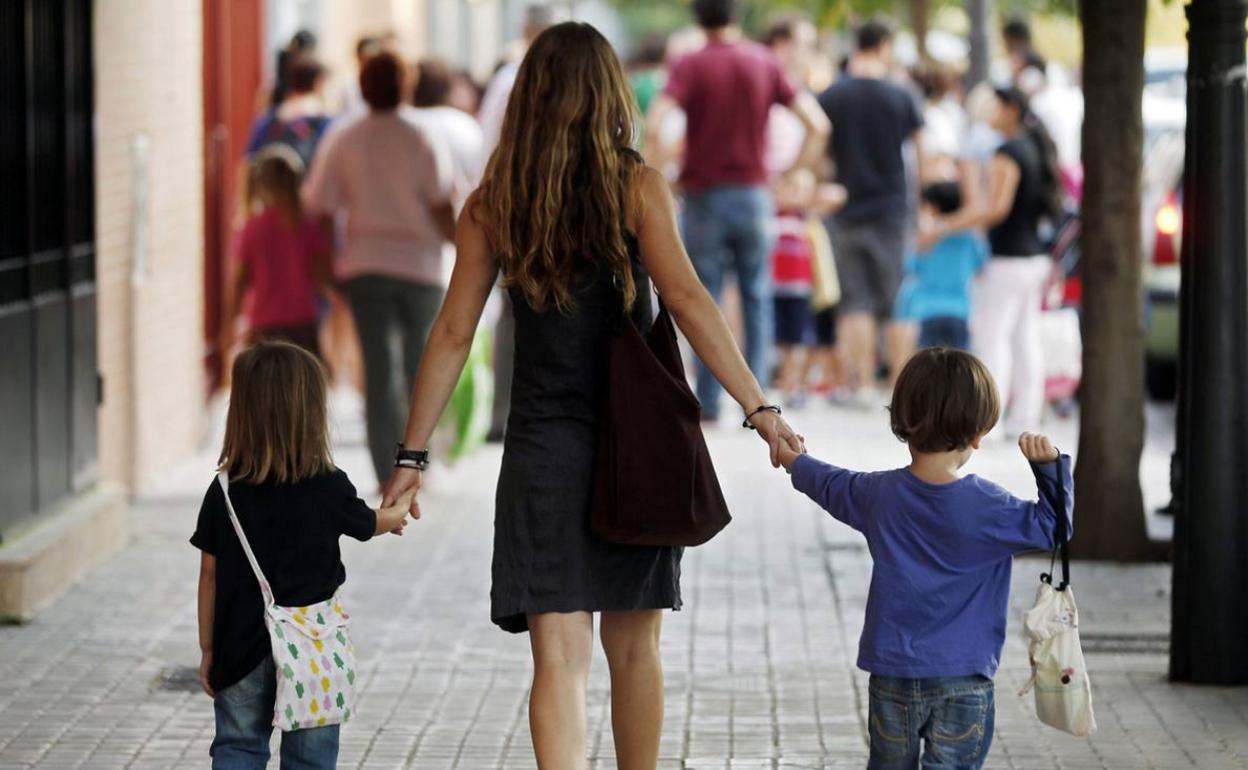 Una madre acompaña a sus hijos al colegio en el primer día de clase. 