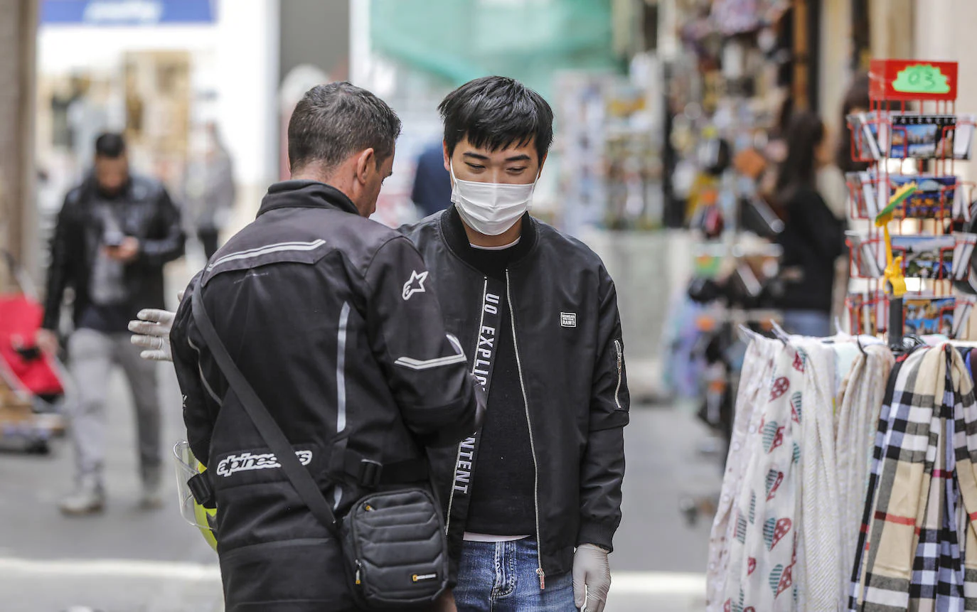 Un hombre pasea con guantes y mascarilla en el centro de la ciudad. 