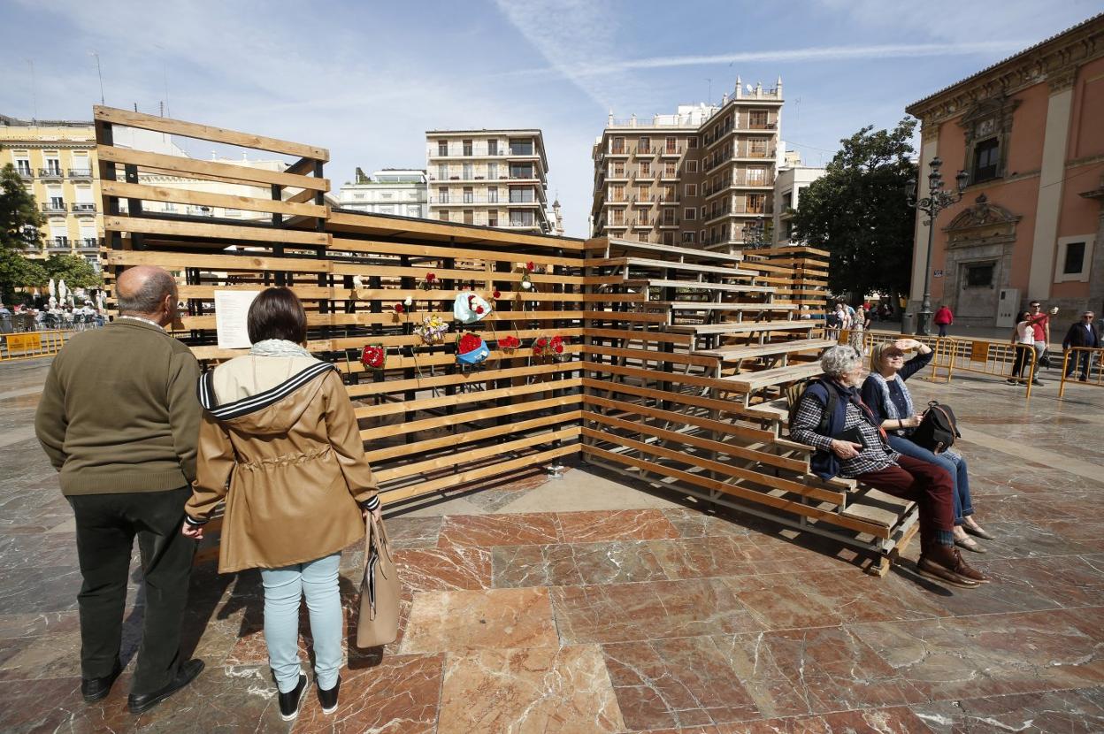 Unos turistas observan parte de la estructura de los ramos en la plaza de la Virgen. jesús signes
