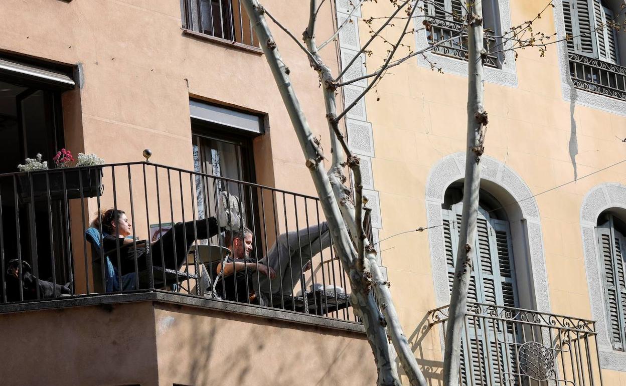 Dos personas toman el sol en un balcón. 