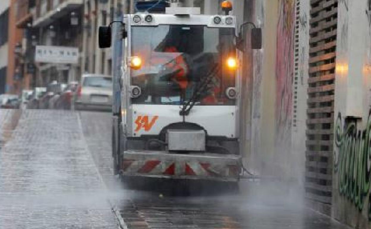 Una máquina de limpieza baldea la calle en Valencia. 