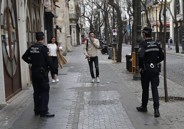 Dos agentes se dirigen a dos viandantes, ayer en la calle San Vicente Mártir. jesús signes