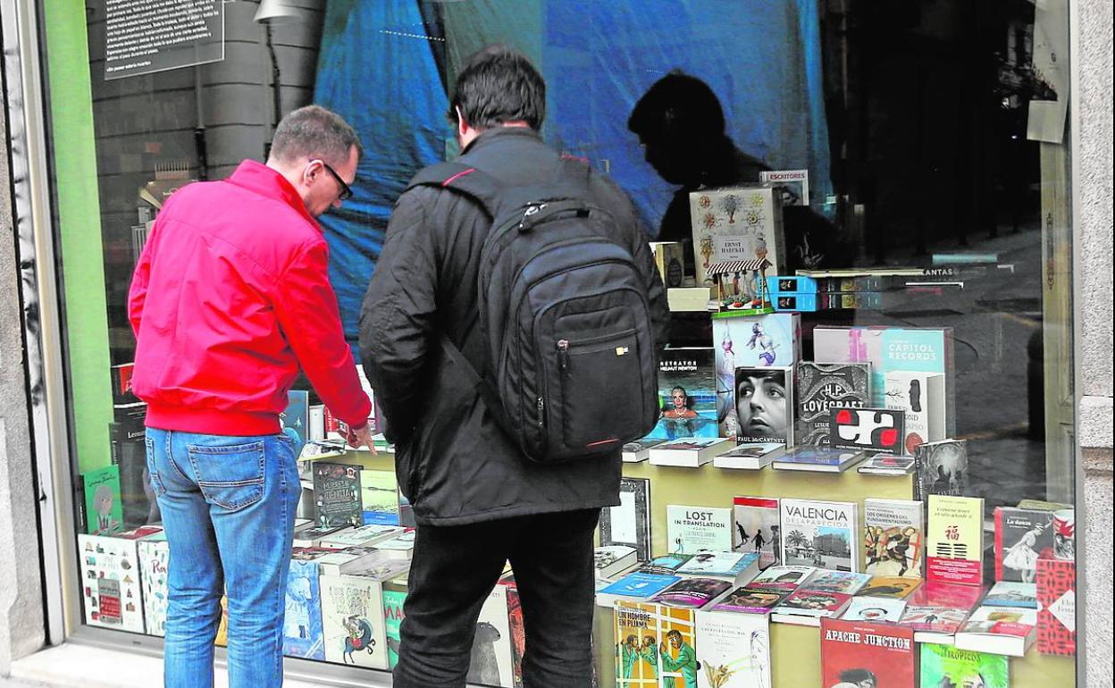 Dos hombres delante del escaparate de una librería. 