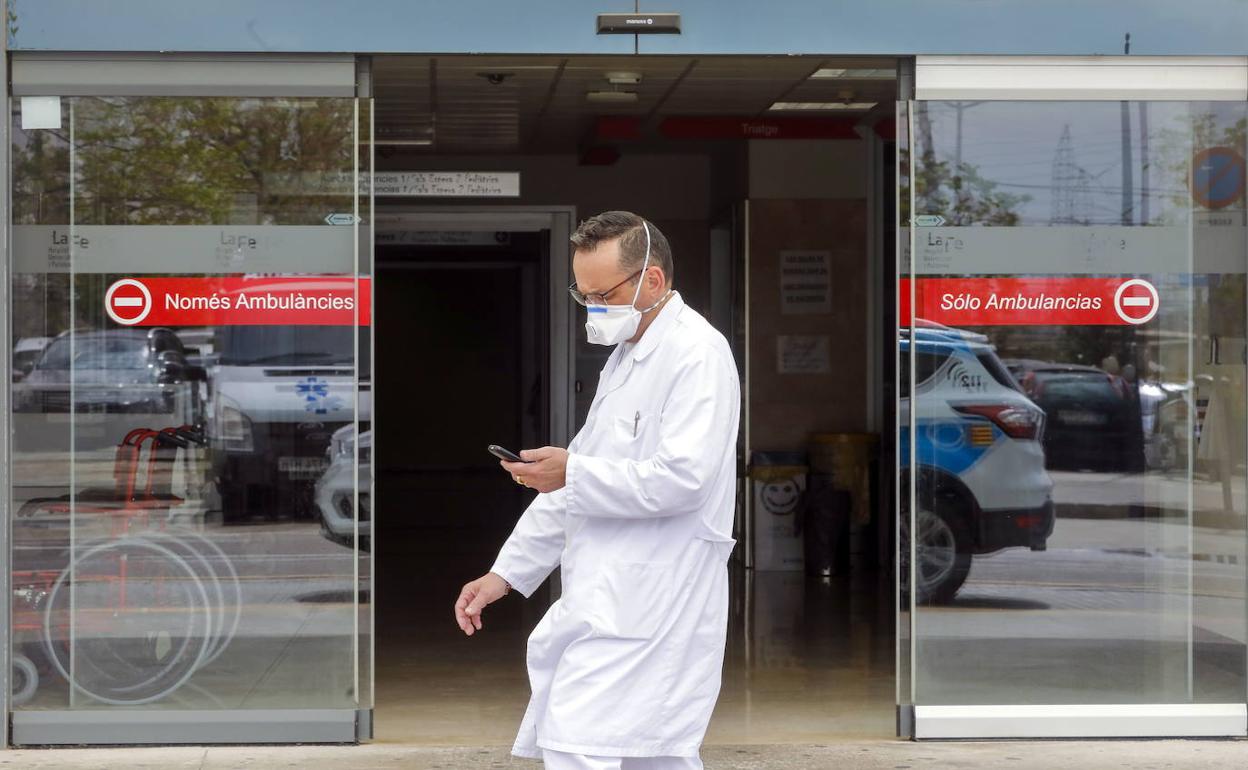 Un m édico con mascarilla pasa junto a una de las puertas de La Fe de Valencia