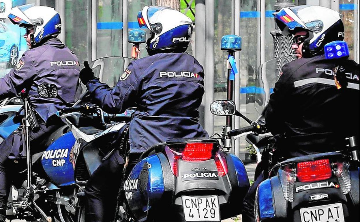 Tres policías nacionales patrullan por una calle. 