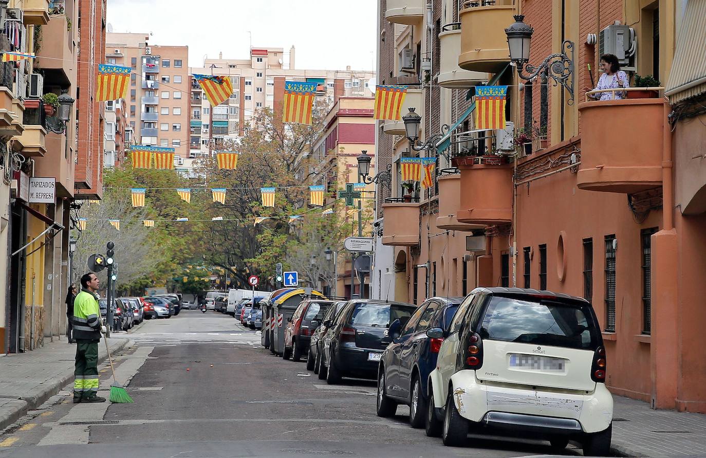 Un barrendero conversa con una mujer asomada al balcón. 