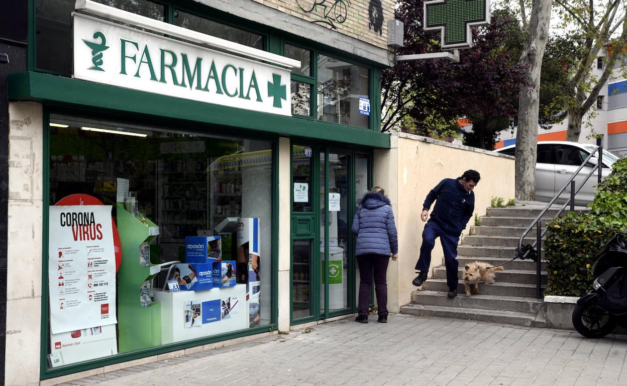 Una mujer en la entrada de una Farmacia, abierta por ser esencial.