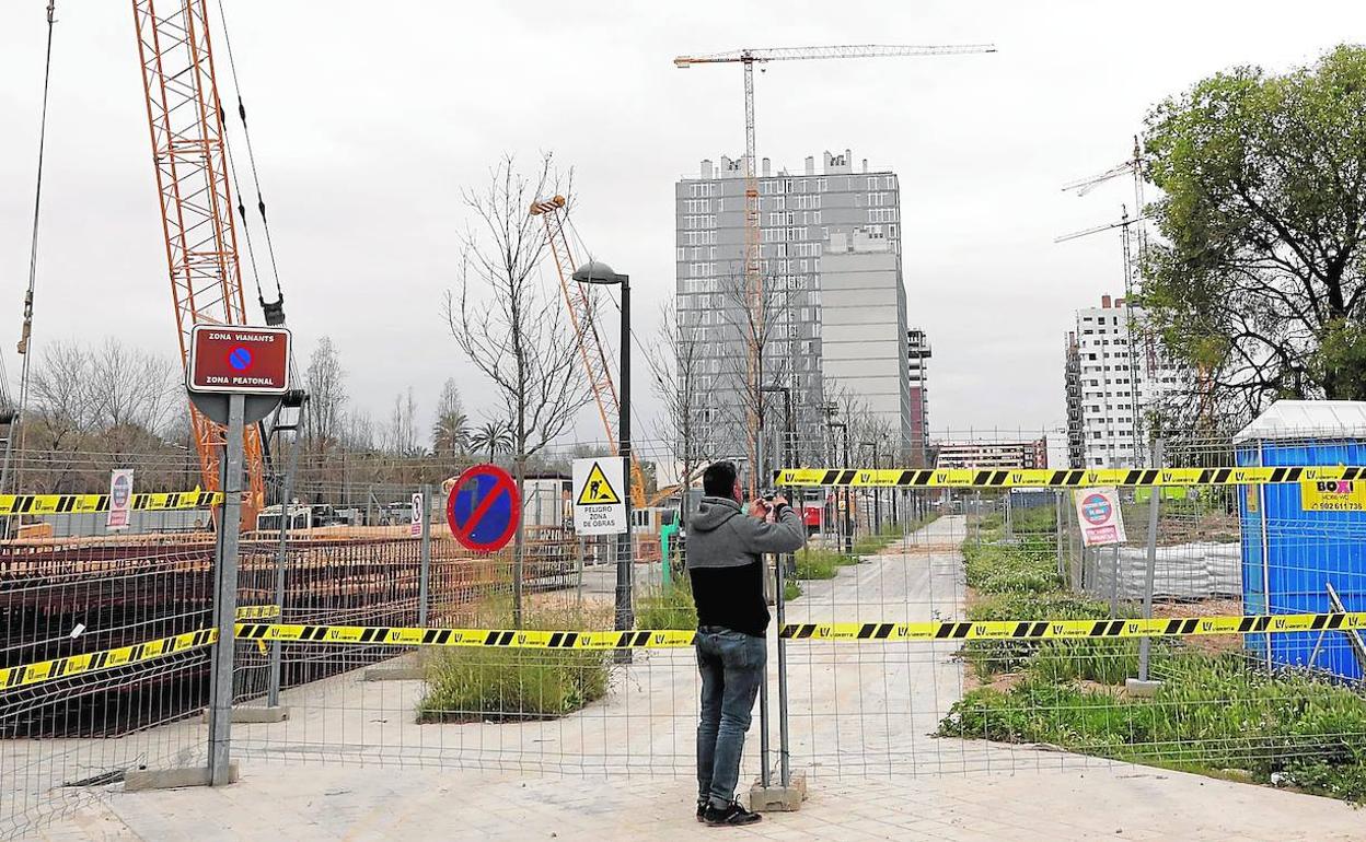 Un trabajador cierra un vallado de una obra en construcción.