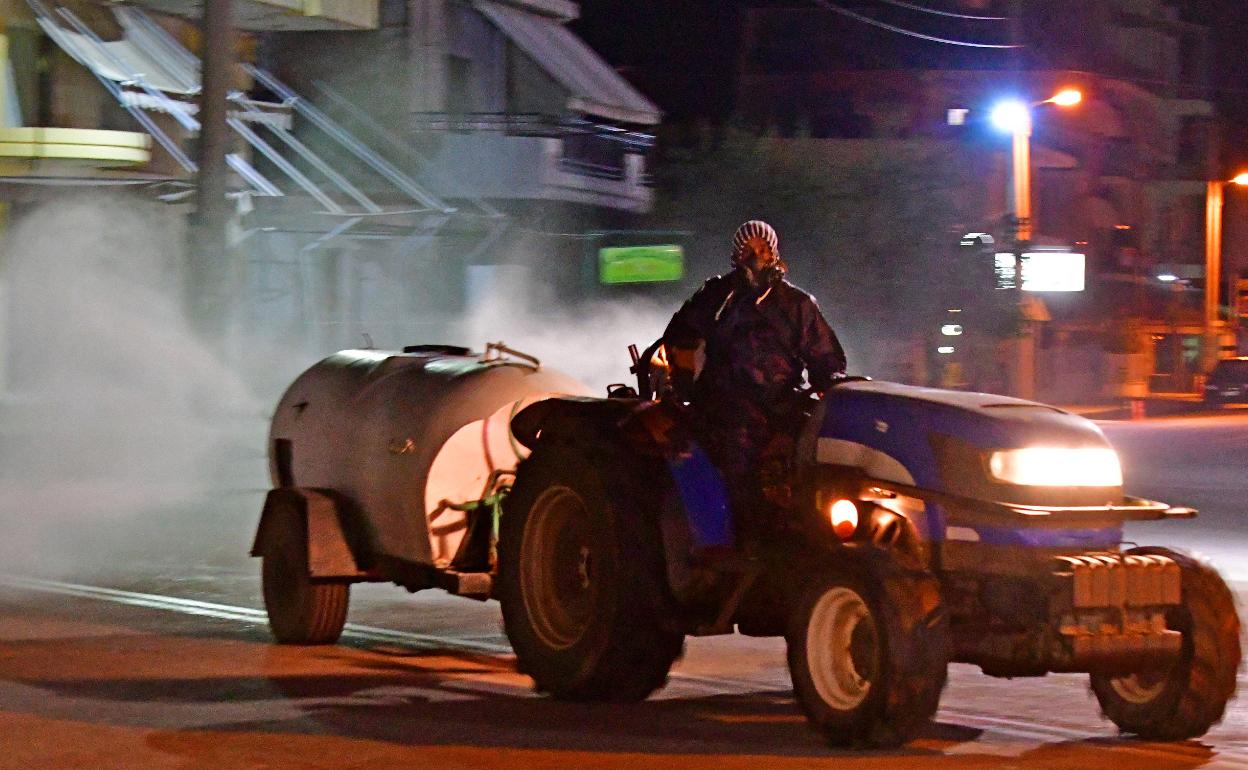 Un agricultor desinfecta una calle con un tractor. 