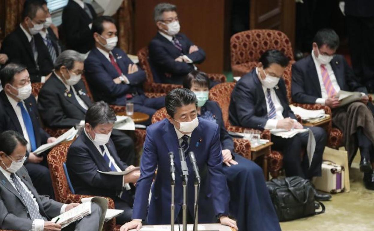 El primer ministro japonés, con mascarilla. El resto de político, también. 