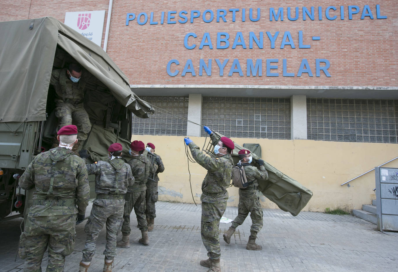 Militares del ejército colocan los materiales necesarios para adecuar el polideportivo del Cabanyal en un albergue para personas sin techo. 