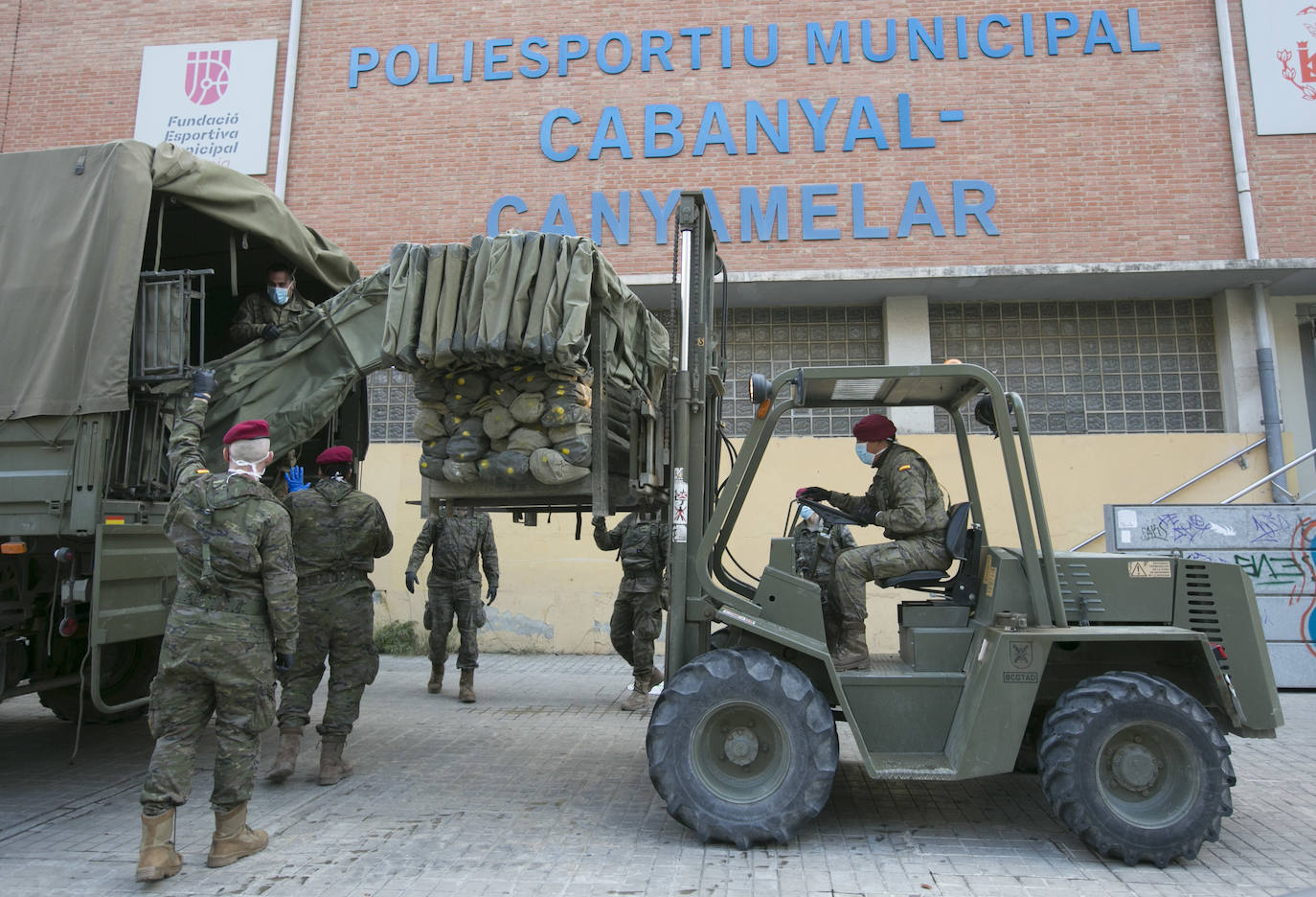 Militares del ejército colocan los materiales necesarios para adecuar el polideportivo del Cabanyal en un albergue para personas sin techo. 