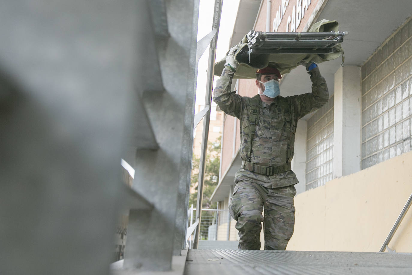 Militares del ejército colocan los materiales necesarios para adecuar el polideportivo del Cabanyal en un albergue para personas sin techo.