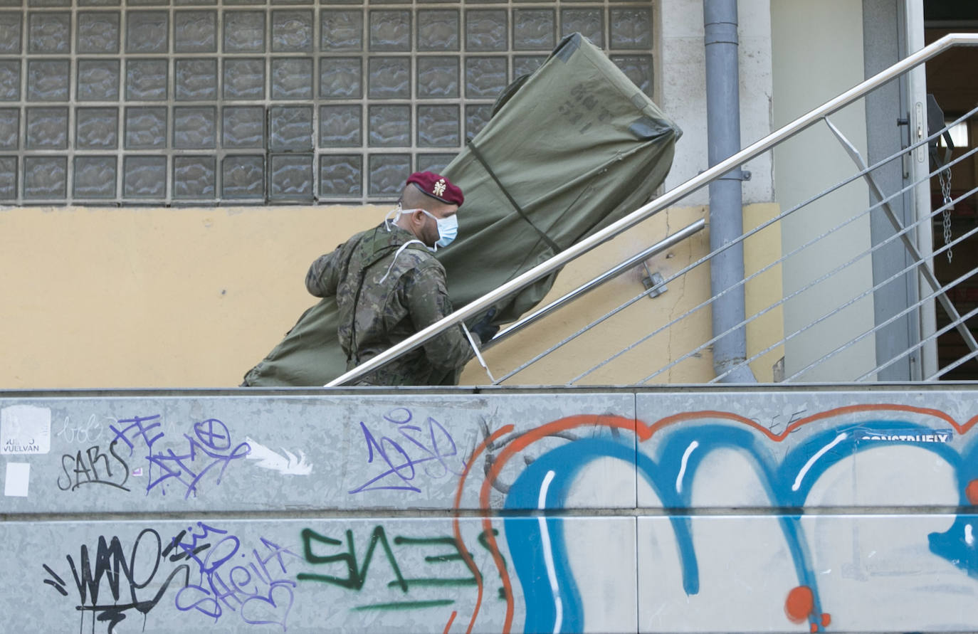 Militares del ejército colocan los materiales necesarios para adecuar el polideportivo del Cabanyal en un albergue para personas sin techo.