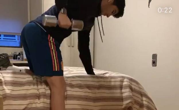 El futbolista, apoyado en la cama para entrenar con pesas.