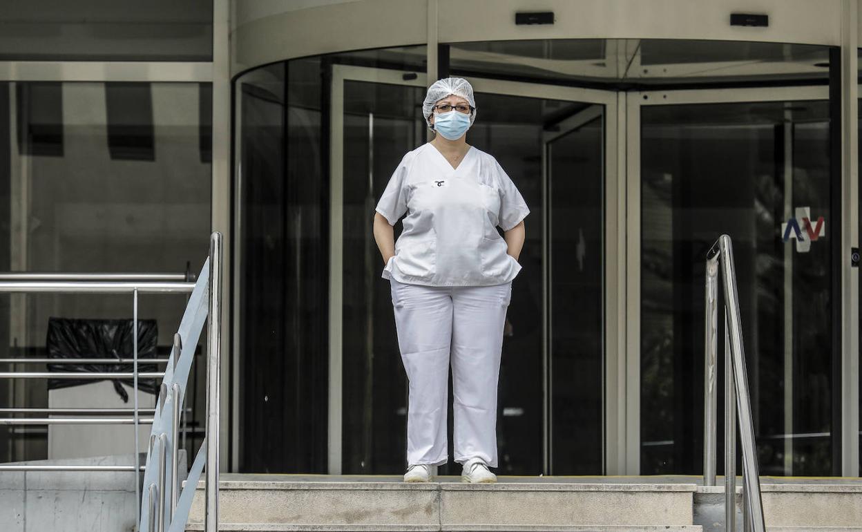 Una sanitaria se protege con mascarilla y gorro en la entrada del Hospital Doctor Peset de Valencia.