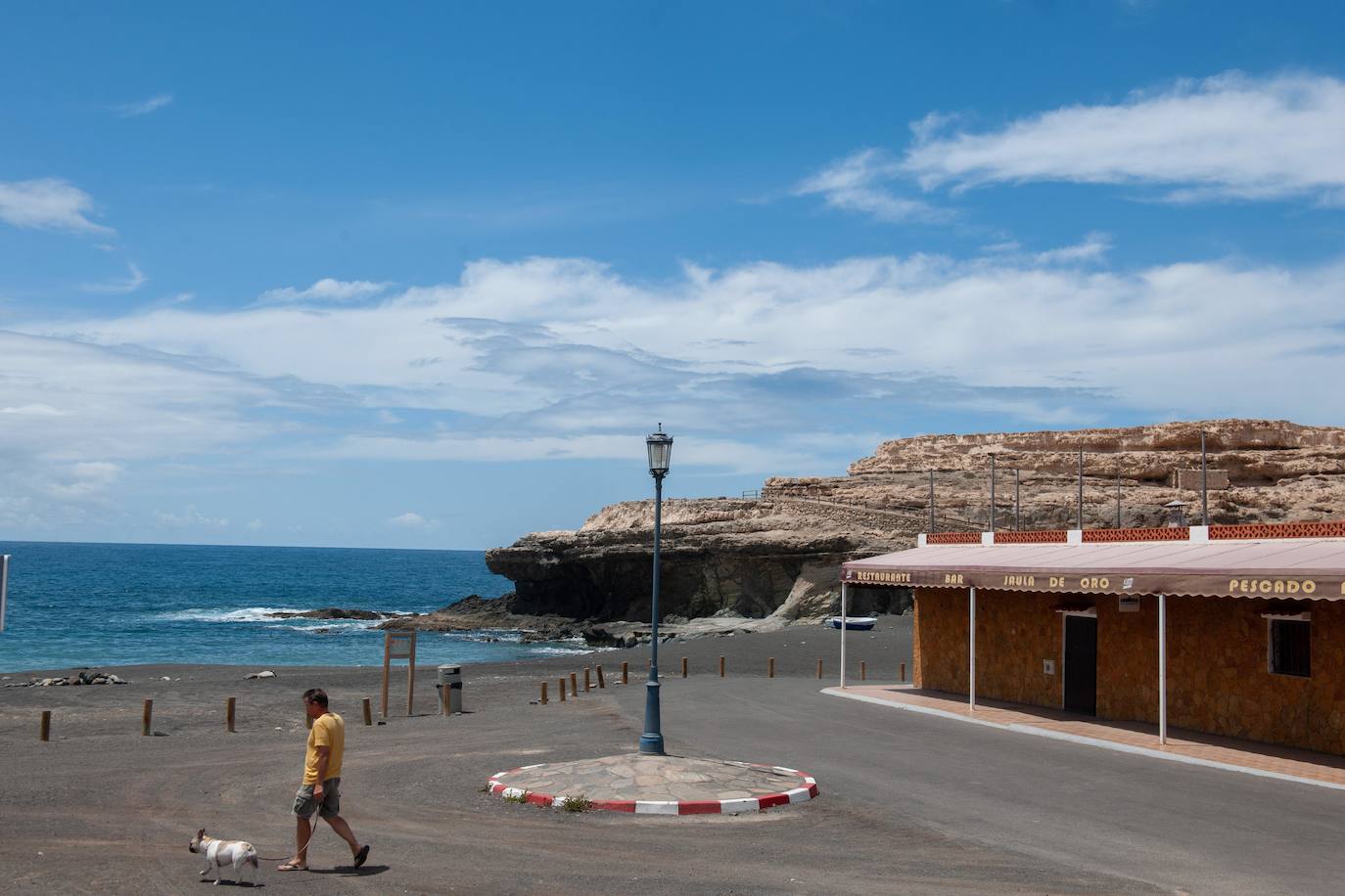 Un hombre pasea a su perro en la localidad de Ajuy, en el municipio de Pájara (Fuerteventura), habitualmente lleno de turistas. 