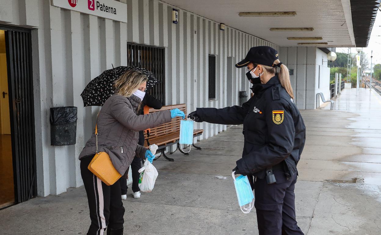 Una policía entrega una mascarilla a una mujer en la estación de metro de Paterna. 