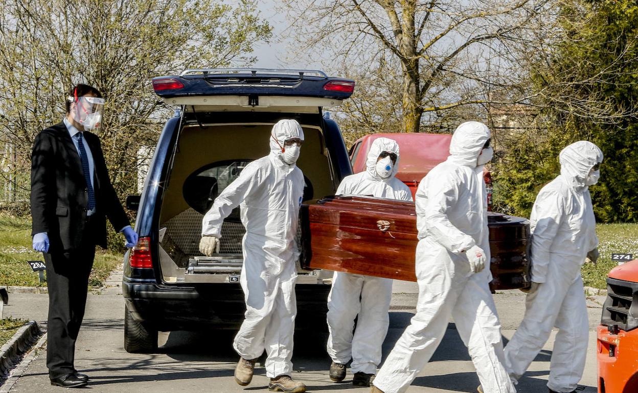 Empleados de una empresa funeraria proceden a inhumar a un fallecido . 