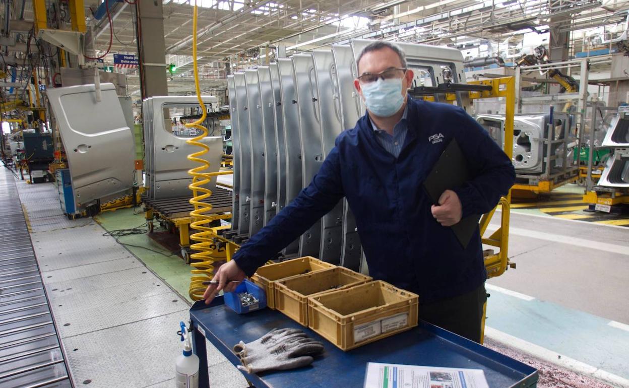 Un trabajador en una fábrica de vehículos con mascarilla.