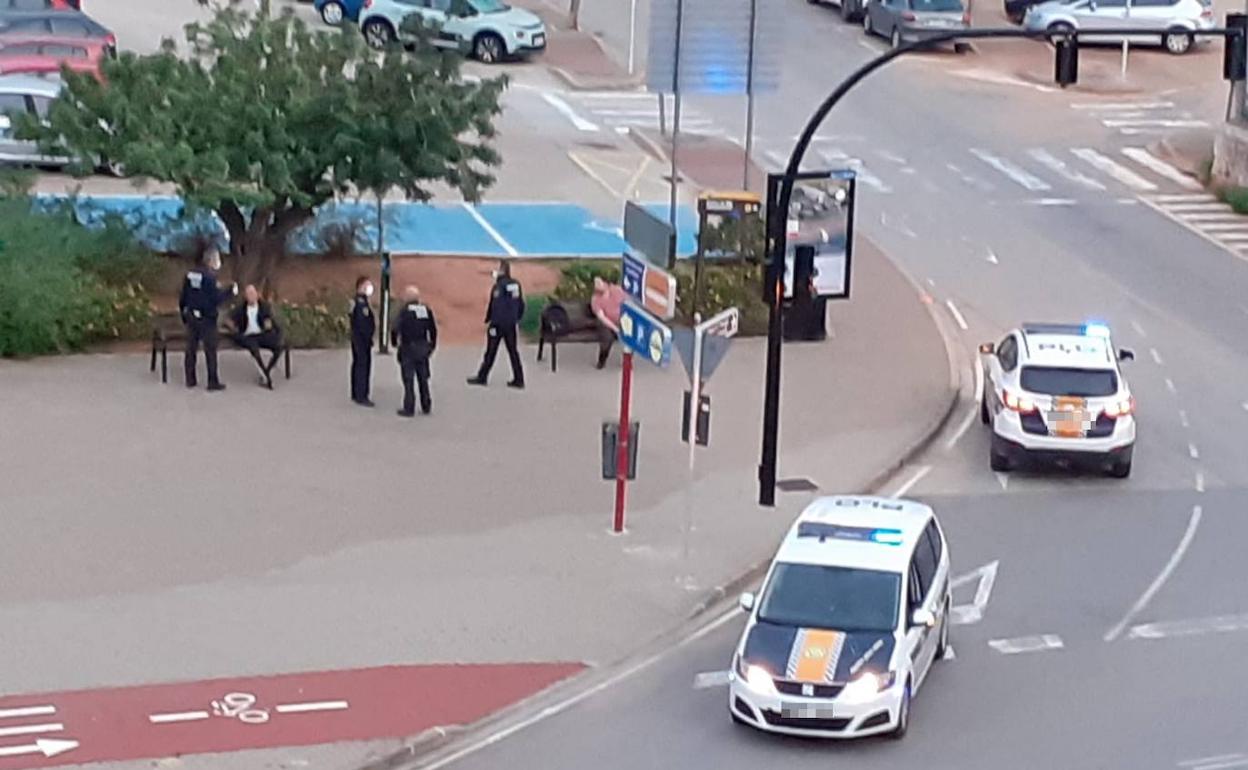 Agentes de la policía identificando a varias personas que están sentadas en unos bancos de Dénia. 