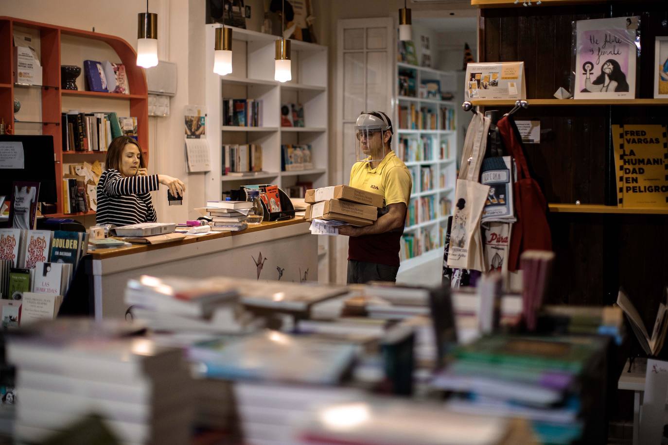 La propietaria de la librería La Rossa, Alodia Clemente, gestiona un pedido con un trabajador de un servicio de mensajería. Las librerías celebran el Día del Libro cerradas al público debido al estado de alarma y con la única posibilidad de gestionar pedidos online al no entrar en la categoría de actividad esencial