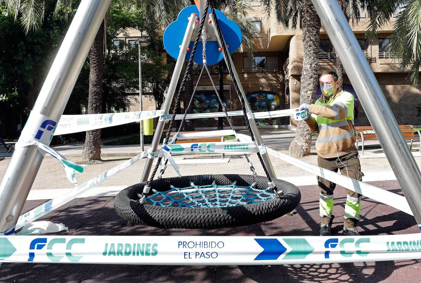 Un operario precinta un columpio en una parque en Valencia. A partir del domingo 26 de abril, y tras pasar seis semanas confinados en casa, los menores de 14 años podrán salir una hora a la calle, a un kilómetro de su domicilio y usar bicis y patinetes. No podrán jugar en parques y jardines, ni utilizar columpios ni juegos infantiles con otros menores