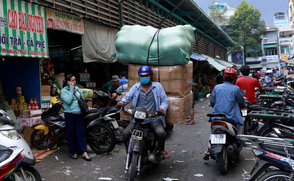 Motocicletas y peatones en un mercado de la ciudad de Ho Chi Minh (Vietnam), tras el levantarse las medidas de confinamiento.