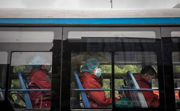 Viajeros de un autobús en China, todos con mascarillas. 