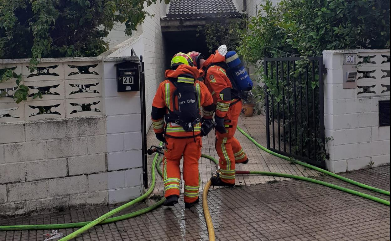 Bomberos acceden a la vivienda para sofocar las llamas. 