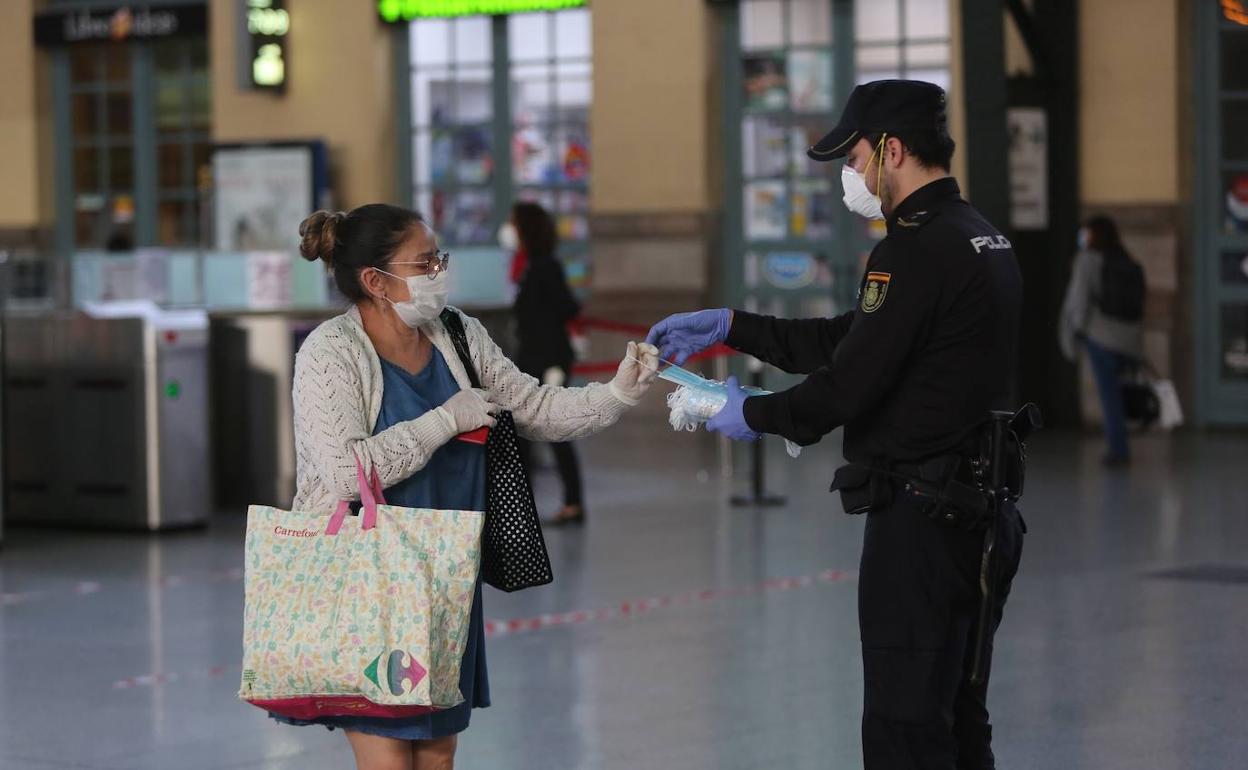 Un agente de la Policía Nacional reparte mascarillas en la Estación del Norte de Valencia. 