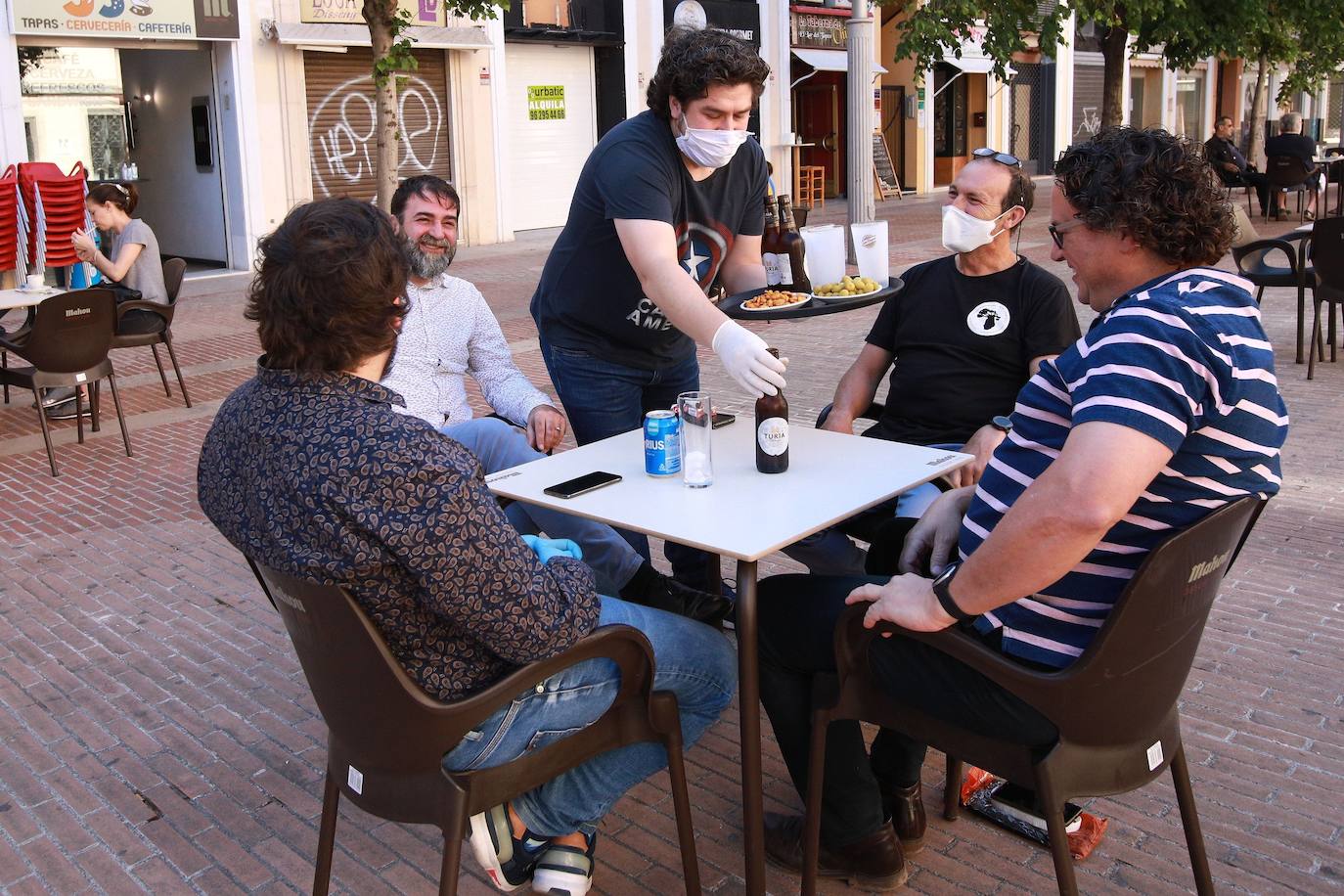 La Comunitat no ha pasado en su conjunto a la fase 1 de la desescalada, según comunicó el pasado viernes el Gobierno en una comparecencia ofrecida entre el ministro de Sanidad, Salvador Illa, y el director técnico, Fernando Simón. Sin embargo, algunas comarzas valencianas sí comenzaban este lunes 11 de mayo el camino hacia la 'nueva normalidad'. En la imagen, vista general de una terraza este lunes por la mañana en Gandía, con la mayoría de la hostelería y comercios abiertos con restricciones. 