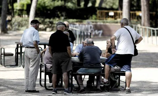 Personas mayores juegan al dominó en un parque. 